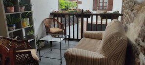A balcony with wicker furniture, a glass table, and potted plants. - Hostal Mendaurpe (Ituren)
