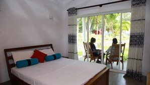 Un dormitorio con una cama grande, cabecera de madera y vista a un patio con mesa y sillas.