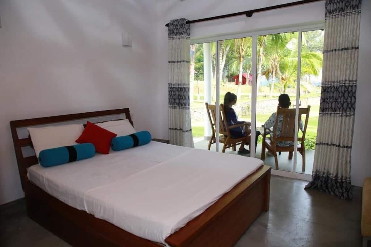 A bedroom with a large bed, a wooden headboard, and a view of a patio with a table and chairs.