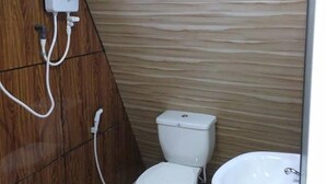 Un baño pequeño con inodoro, bidé y un secador de manos en la pared.