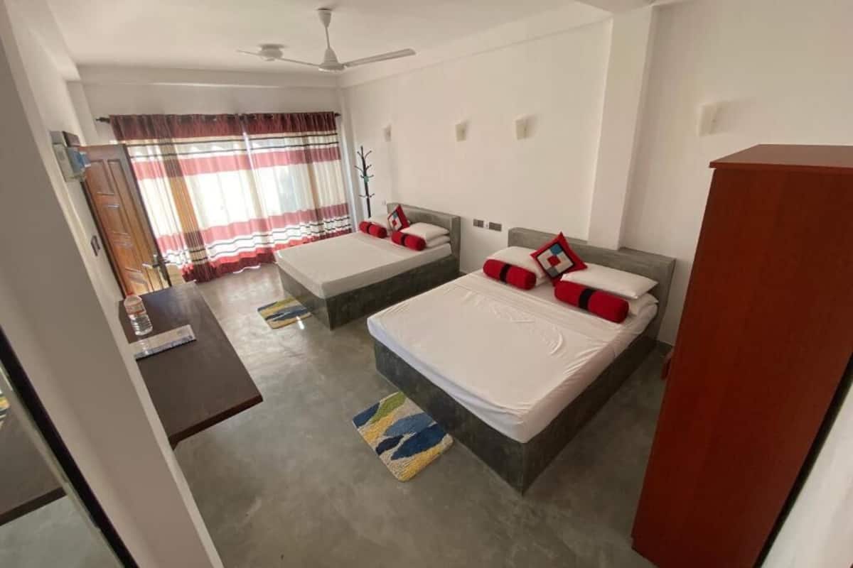 A bedroom with two beds, a wardrobe, a desk, and a ceiling fan.
