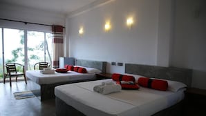 Habitación de hotel con dos camas, un área de descanso con una silla y vistas al exterior.