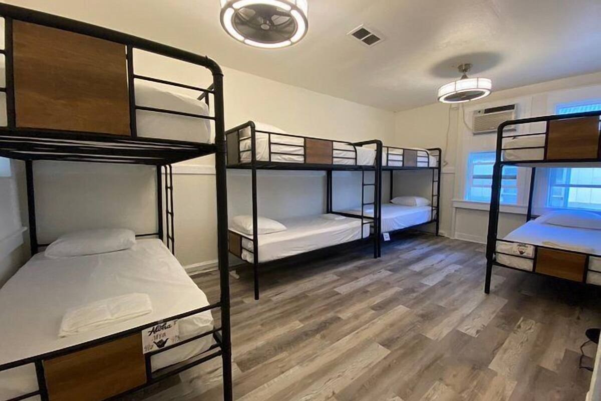 A room with bunk beds, wooden flooring, and ceiling lights.
