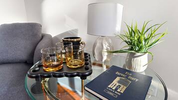 Une table en verre sur laquelle repose un livre intitulé « L’histoire de Carver » et trois verres contenant un liquide ambré.