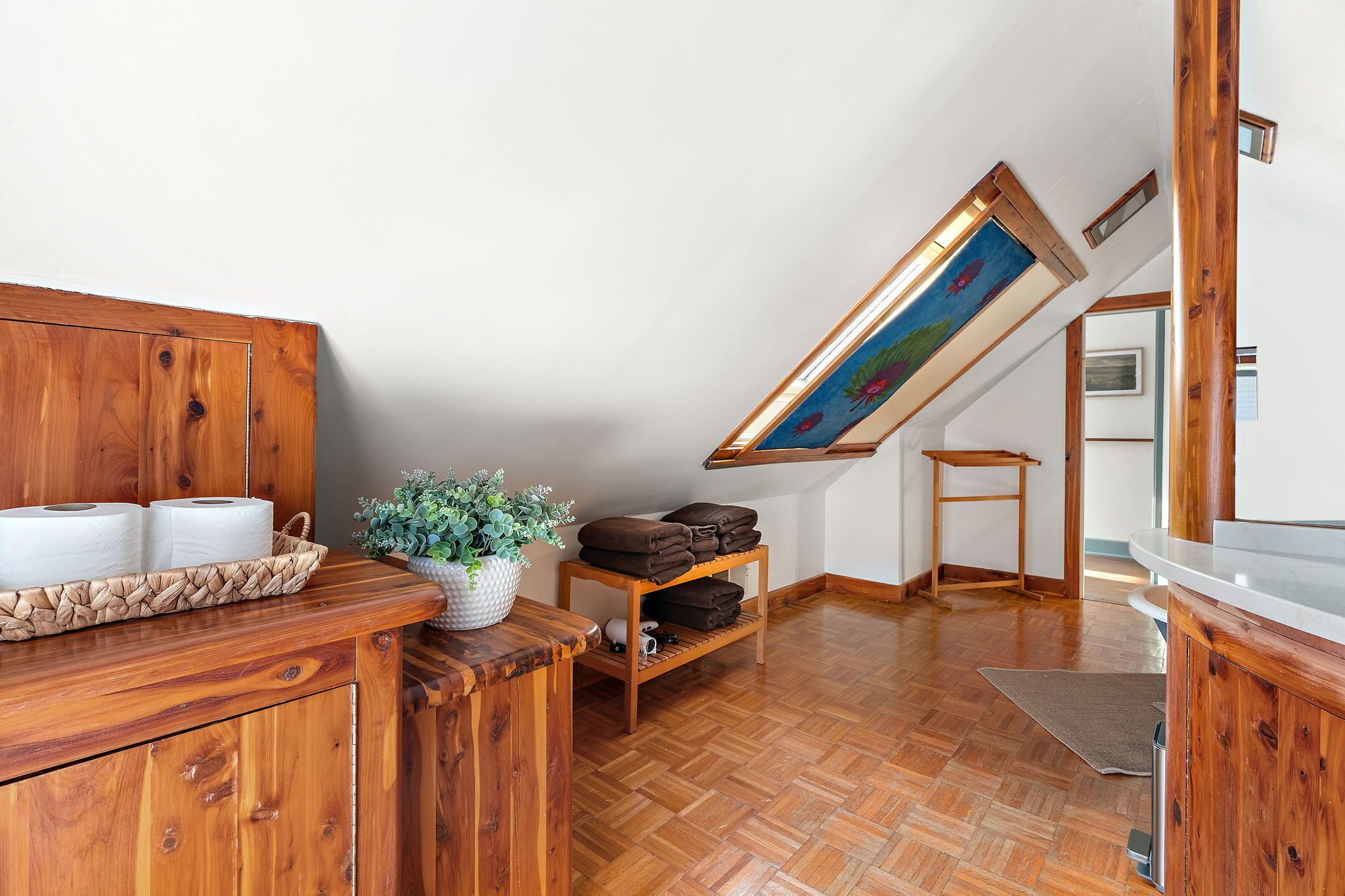 Un intérieur en bois avec un ventilateur de plafond, une étagère avec des serviettes et une plante en pot.
