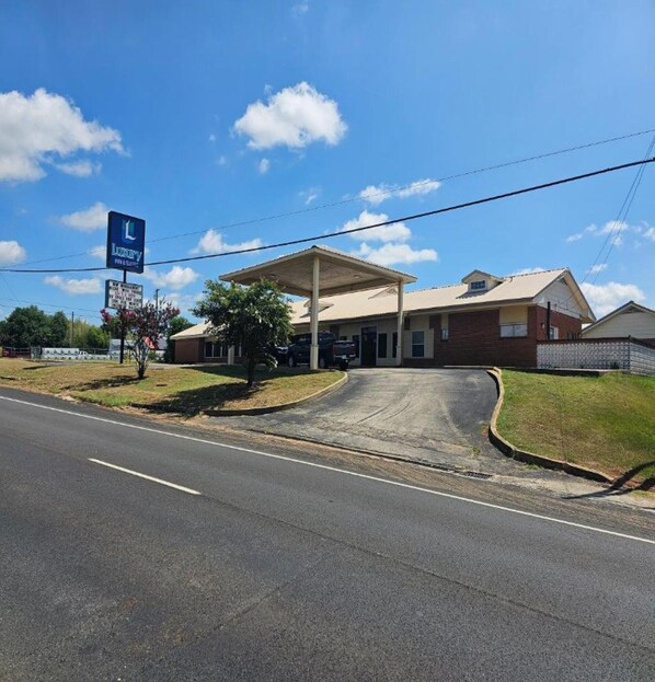 A building with a covered parking area and a sign for a hotel. - Luxury Inn & Suites and RV Park  (Nacogdoches)