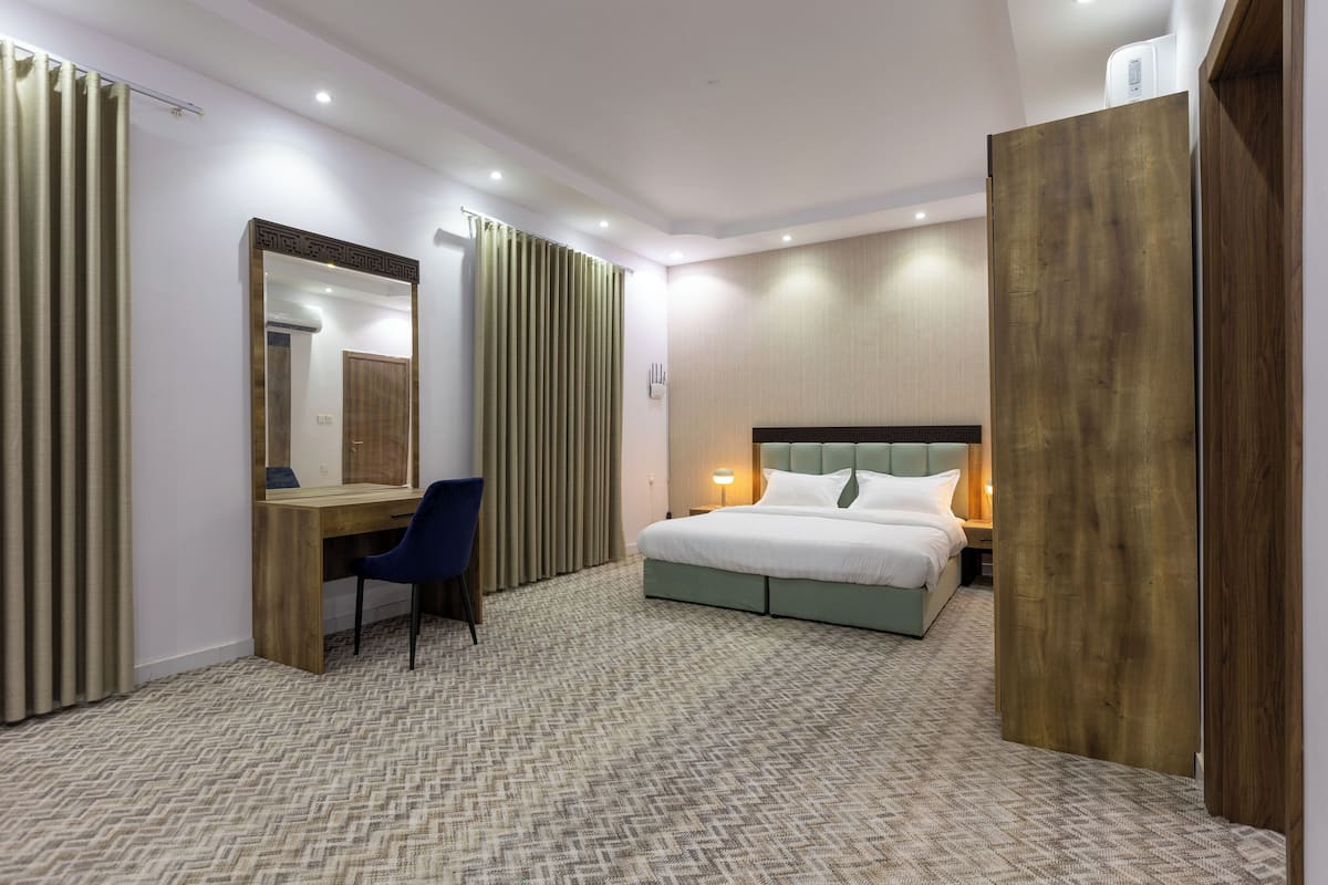 Una habitación de hotel con cama, escritorio, silla y armario.