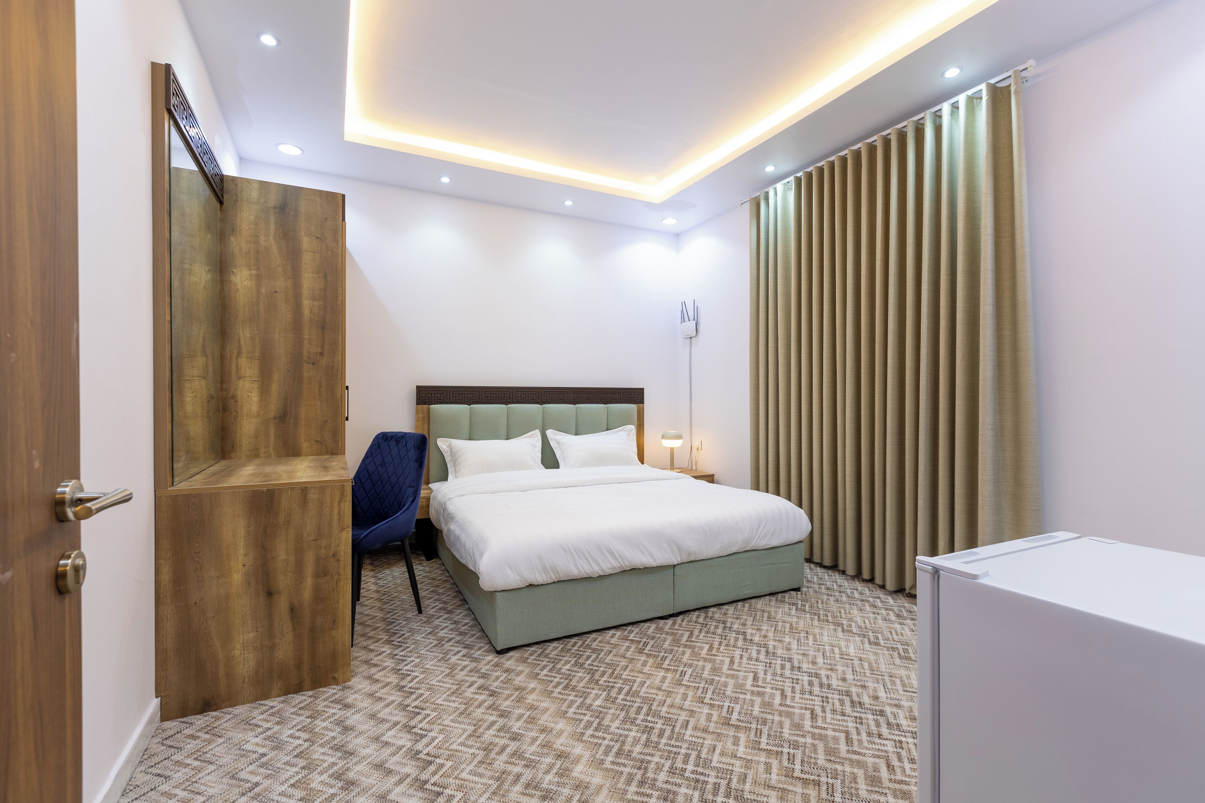 Una habitación de hotel moderna con una cama grande, un armario de madera, un escritorio y una silla.