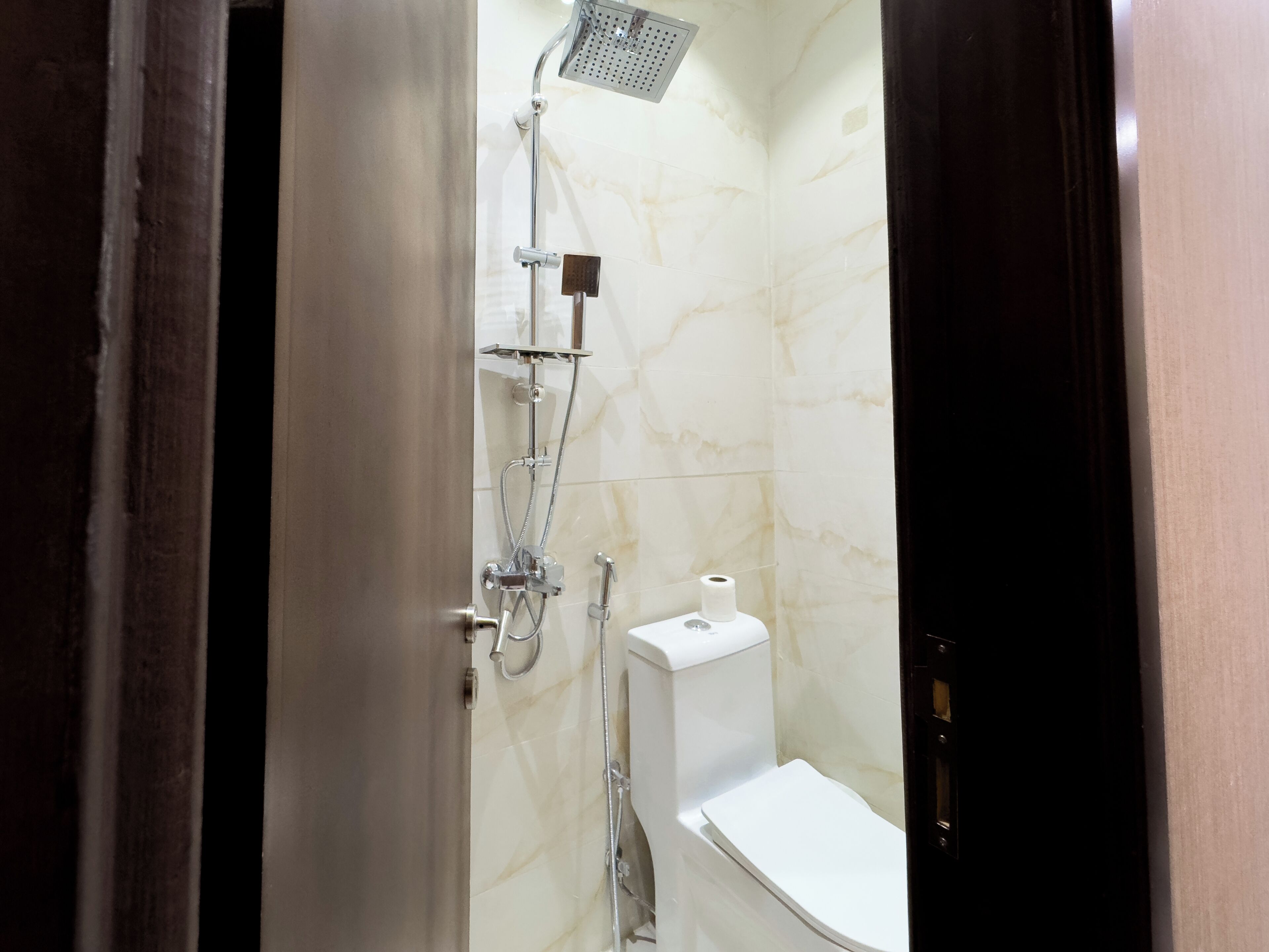 A bathroom with a shower, toilet, and a towel rack.