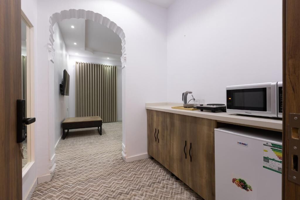 A compact kitchen with a microwave, refrigerator, and a bench in the corner.