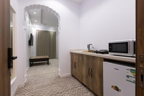 A compact kitchen with a microwave, refrigerator, and a bench in the corner. - Al-Jamwaut B - Nozol Noor 7 (Madinah)