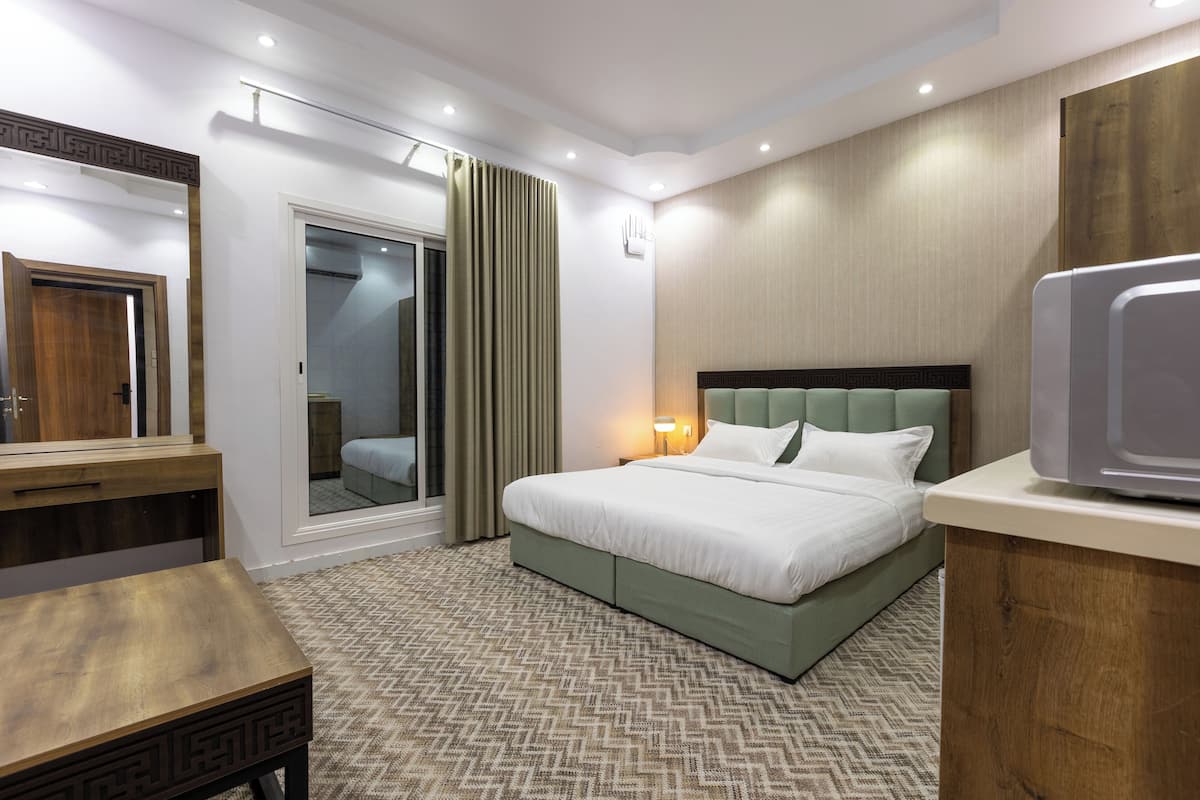 Habitación de hotel moderna con una cama grande, un escritorio de madera, un espejo y vistas al exterior.