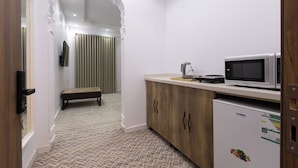 A compact kitchen with a microwave, refrigerator, and a bench. - Al-Jamwaut B - Nozol Noor 7 (Madinah)