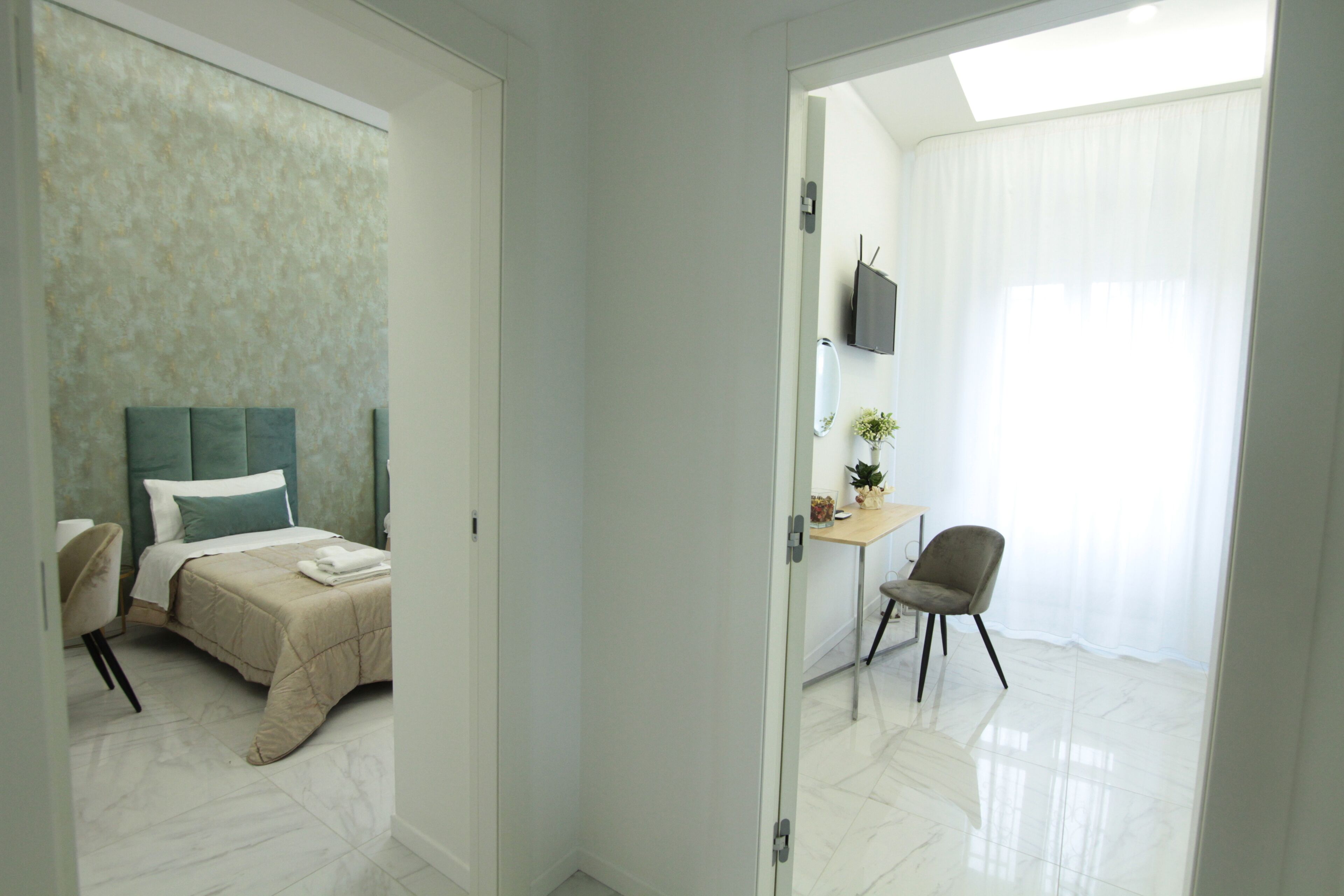 Een hotelkamer met een bed, een bureau, een stoel en een televisie aan de muur.