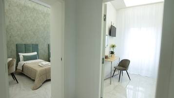 Een hotelkamer met een bed, een bureau, een stoel en een televisie aan de muur.