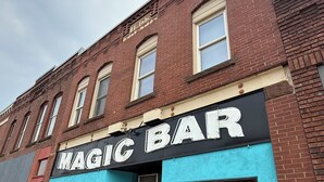 En murstensbygning med et skilt, der siger "MAGIC BAR" med store hvide bogstaver.