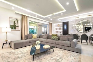 A modern living room with a sectional sofa, a coffee table, and a large mirror.