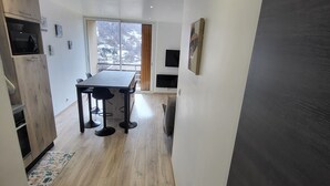A modern kitchen with a dining area, wooden flooring, and a large window offering a view of a snowy landscape. - SEASONAL RENTAL RENOVATED STUDIO 35M2 IN ORCIÈRES (ORCIÈRES)