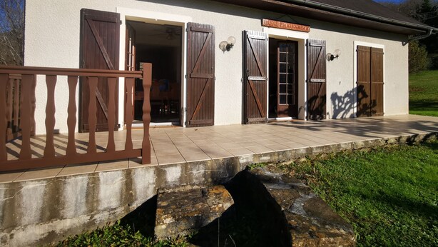 A building with a sign reading "Cureparlodgeia," featuring a large wooden door, a small window, and a balcony with a wooden railing. - House Gure-Phauxagia (Gotein-Libarrenx)