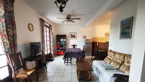 A living room with a dining table, sofa, and a TV. There is a bookshelf and a ceiling fan. - House Gure-Phauxagia (Gotein-Libarrenx)