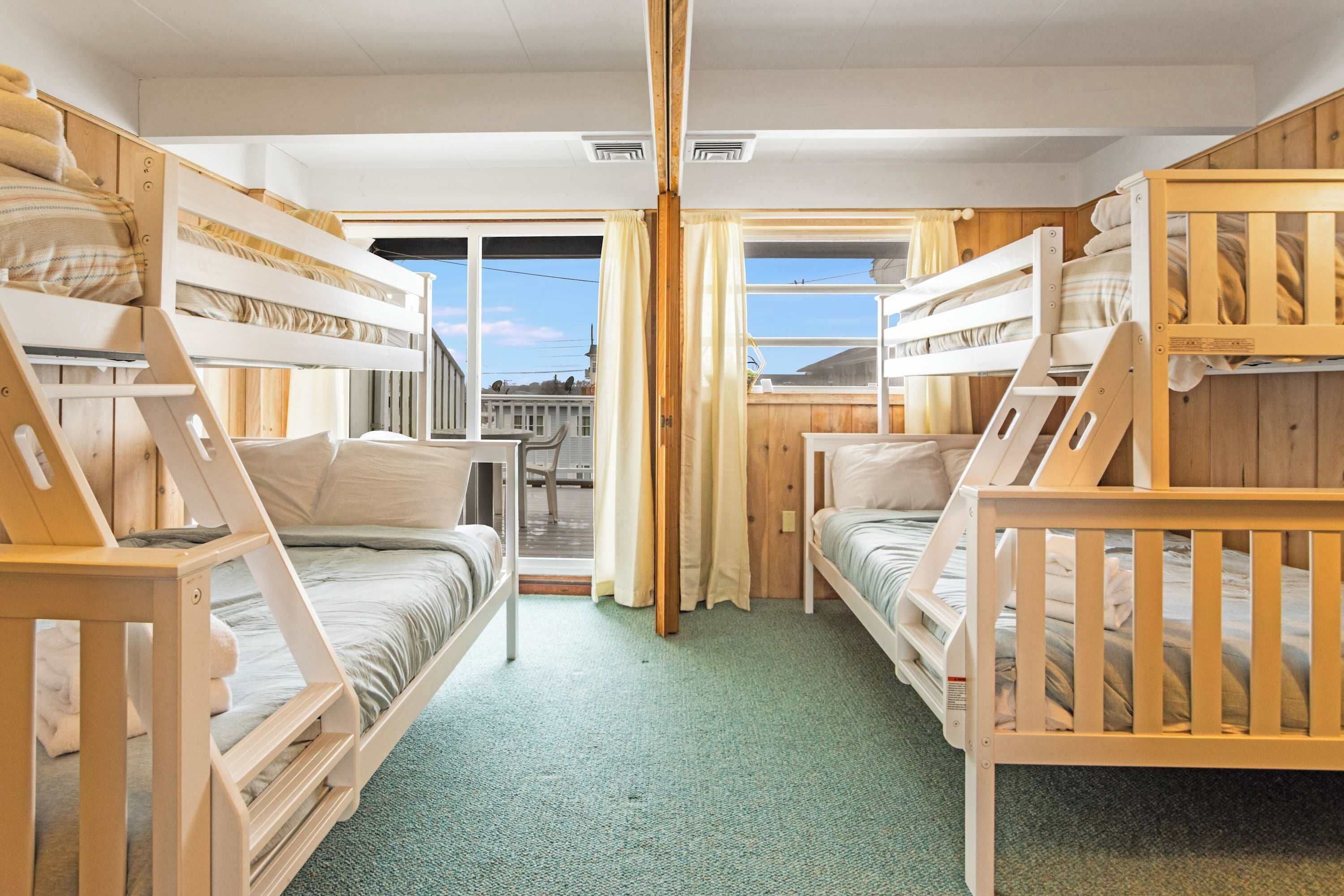 A room with bunk beds, a small table, and a view through a window.