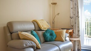 A modern living room with a leather sofa, a small wooden side table, and a floor lamp.