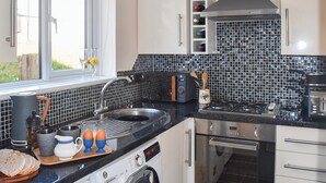 A compact kitchen with a washing machine, a microwave, and a stove.