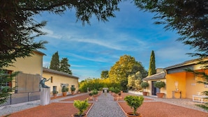 A courtyard with a gravel path, potted plants, and buildings with tiled roofs.