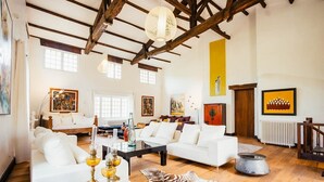A spacious living room with white sofas, a coffee table, and a zebra rug. There are paintings on the walls and a large window providing natural light. - Moulin Des Libellules (Parcoul)