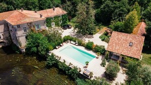 A large estate with a swimming pool, a stone bridge, and lush greenery. - Moulin Des Libellules (Parcoul)