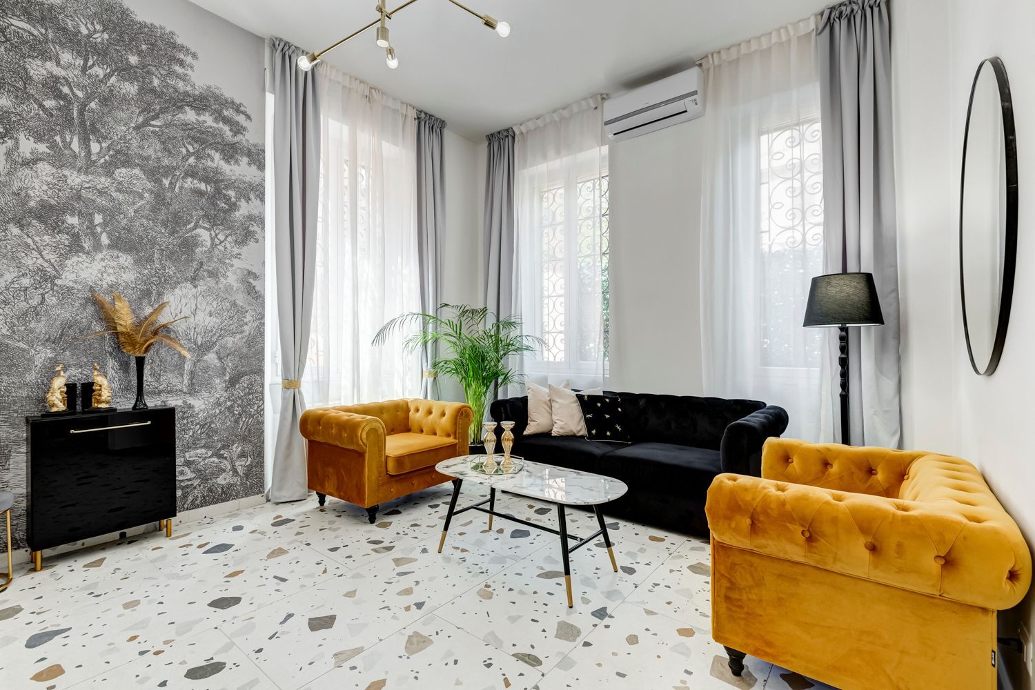 Una sala de estar moderna con un sofá, sillones, una mesa de centro y una planta decorativa.