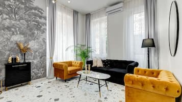 Una sala de estar moderna con un sofá, sillones, una mesa de centro y una planta decorativa.