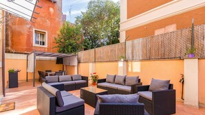 Un patio con mobiliario exterior, incluyendo sofás y sillas, y una pérgola que proporciona sombra.