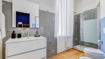 Un bagno moderno con un mobile lavabo bianco, cabina doccia in vetro e parete azzurra.