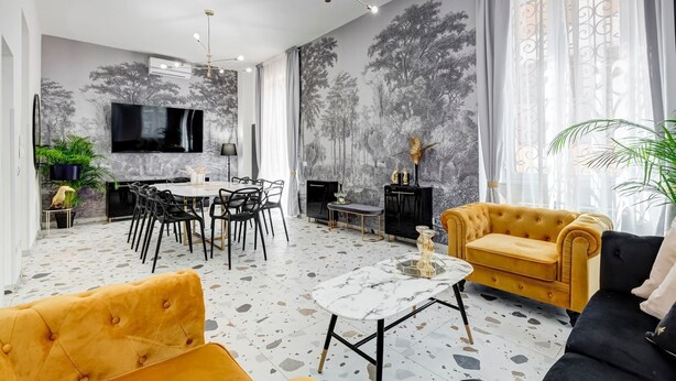 Una sala de estar moderna con comedor, chimenea y un televisor grande montado en la pared.
