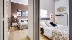 A bedroom with a bed, bedside tables, a mirror, and wall-mounted lights.