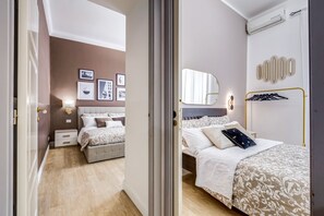 A bedroom with a bed, bedside tables, a mirror, and wall-mounted lights.