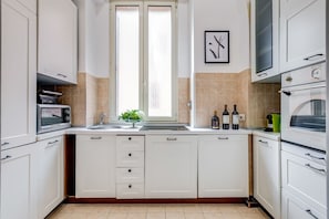 Una cocina moderna con armarios blancos, horno empotrado, microondas y ventana con vistas.