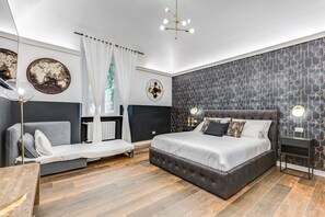A modern bedroom with a large bed, a sofa, a small table, and a decorative wall. - Global Condo - Two Bedroom Villa, Sleeps 6 (Rome)