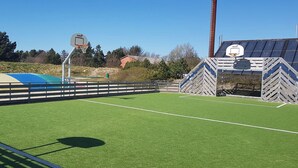Un terrain de sport extérieur équipé d’un panier de basket et de buts de football.