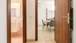Een deur die leidt naar een badkamer met toilet, wastafel en spiegel.
