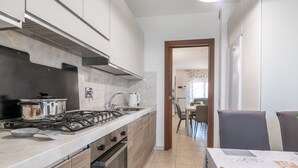 Een moderne keuken met een fornuis, oven en spoelbak. Er is een eethoek met een tafel en stoelen zichtbaar op de achtergrond.