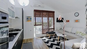 A modern kitchen with a built-in oven and a dining area with a black and white rug. - Marinero-sea Breeze Escape in Zuljana (Ston)