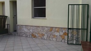 Fachada de edificio con muro de piedra, una ventana y una reja metálica.