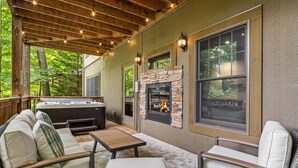 Un patio al aire libre con chimenea de piedra, asientos y un jacuzzi.