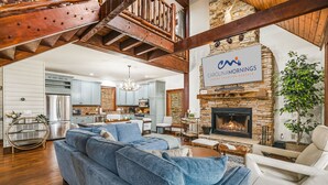 Un salón amplio con un sofá grande azul, una chimenea y una cocina al fondo.