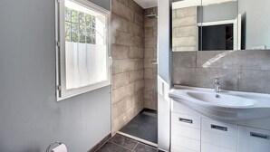 A modern bathroom with a shower, a sink, and a large mirror.