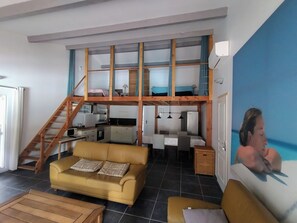 A multi-level living space with a sofa, a dining table, and a kitchen area.