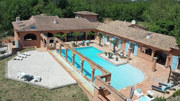 A large outdoor swimming pool with a sun terrace and lounge chairs.