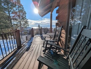 Eine Holzterrasse mit Blick auf eine verschneite Landschaft und Berge.